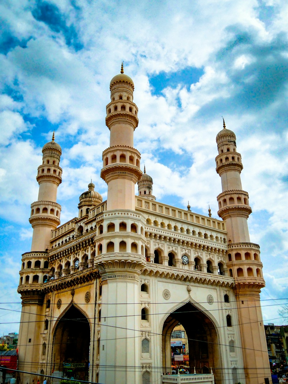 a large white building with towers with Charminar in the background