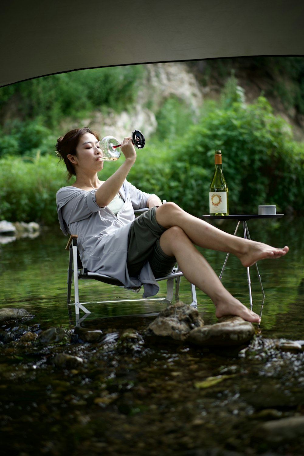 a person sitting in a chair drinking from a bottle