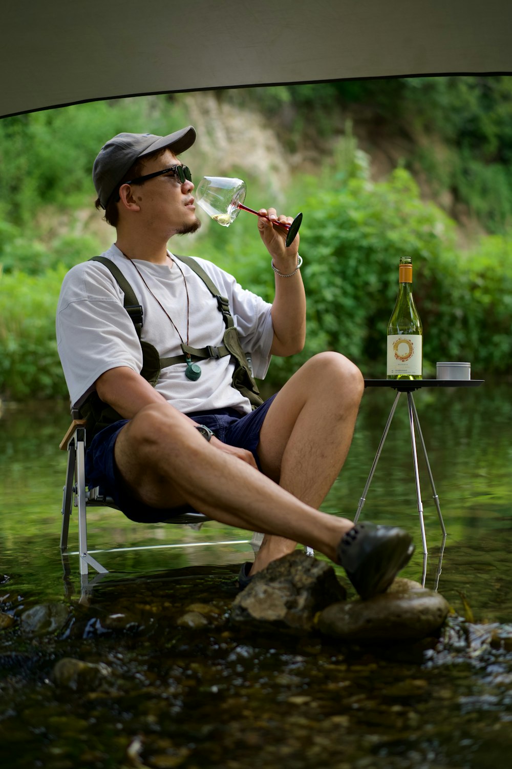 un uomo seduto su una roccia che beve da un bicchiere