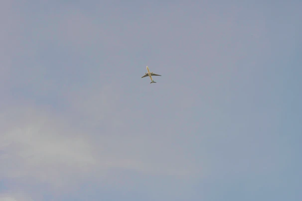 An airplane flying above clouds with a clear blue sky background.