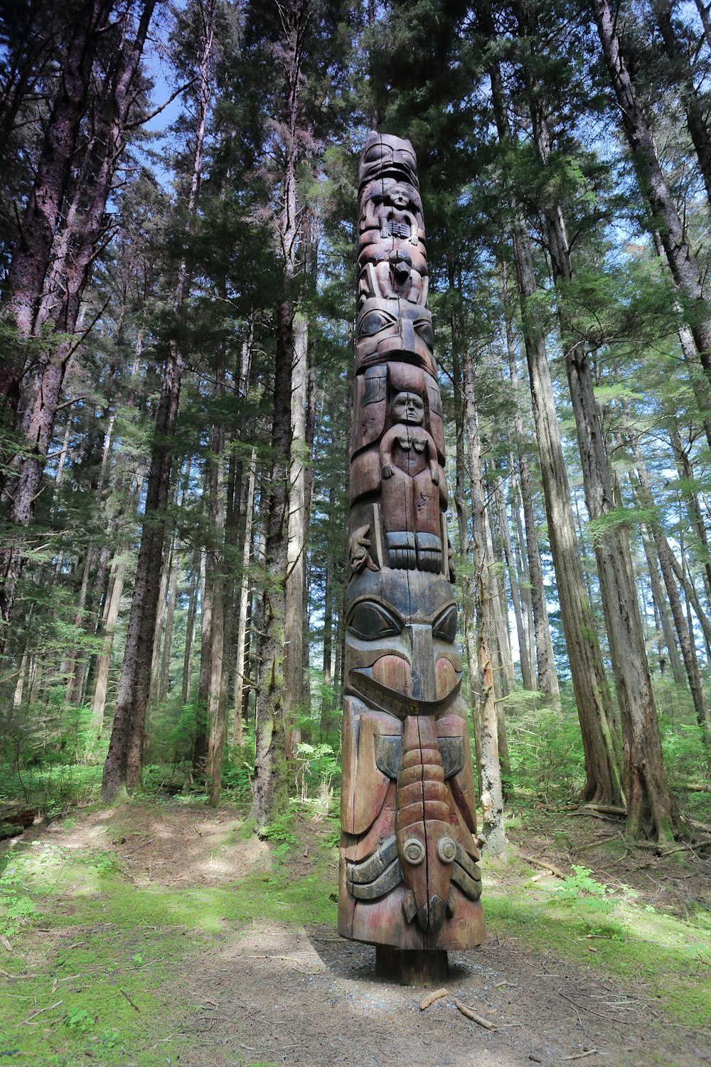 a wood carving of a person with a face on it in a forest