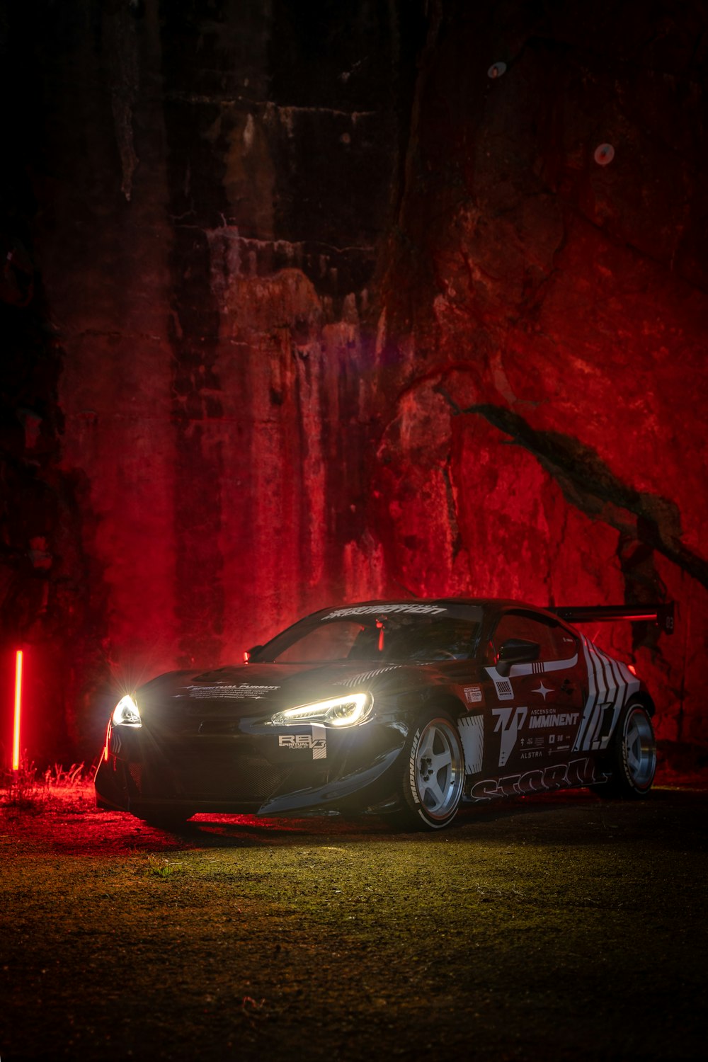 a car parked in front of a red wall with lights