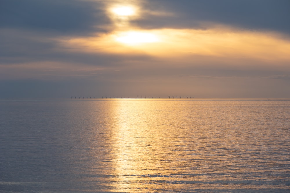 a body of water with a cloudy sky above it