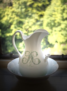 A serene kitchen scene featuring a ceramic pitcher filled with fresh flowers next to matching mugs.