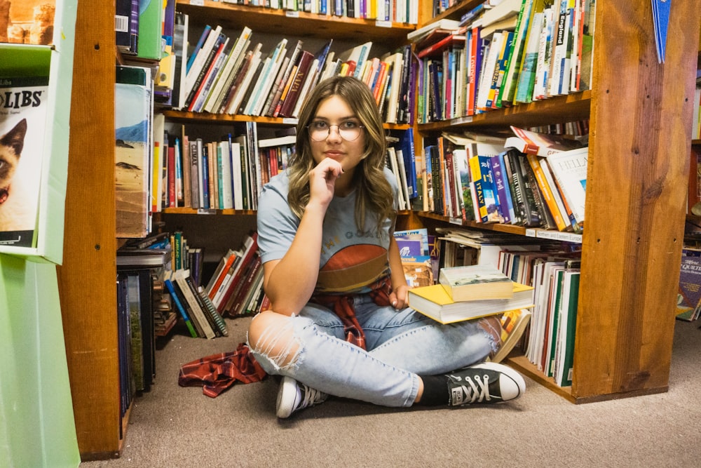 a girl sitting on the floor in front of a bookshelf