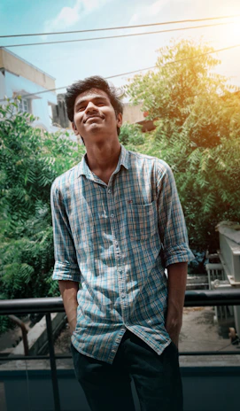 A happy customer wearing a golden cotton shirt, smiling while standing in a sunlit park.