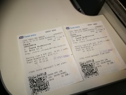 Two Czech train tickets are placed on a white surface. They contain details like departure and destination locations, travel dates, train numbers, and QR codes. Both tickets are for a journey from Česk&eacute; Budějovice to Brno hl.n. The background suggests they are on a flat surface or countertop.