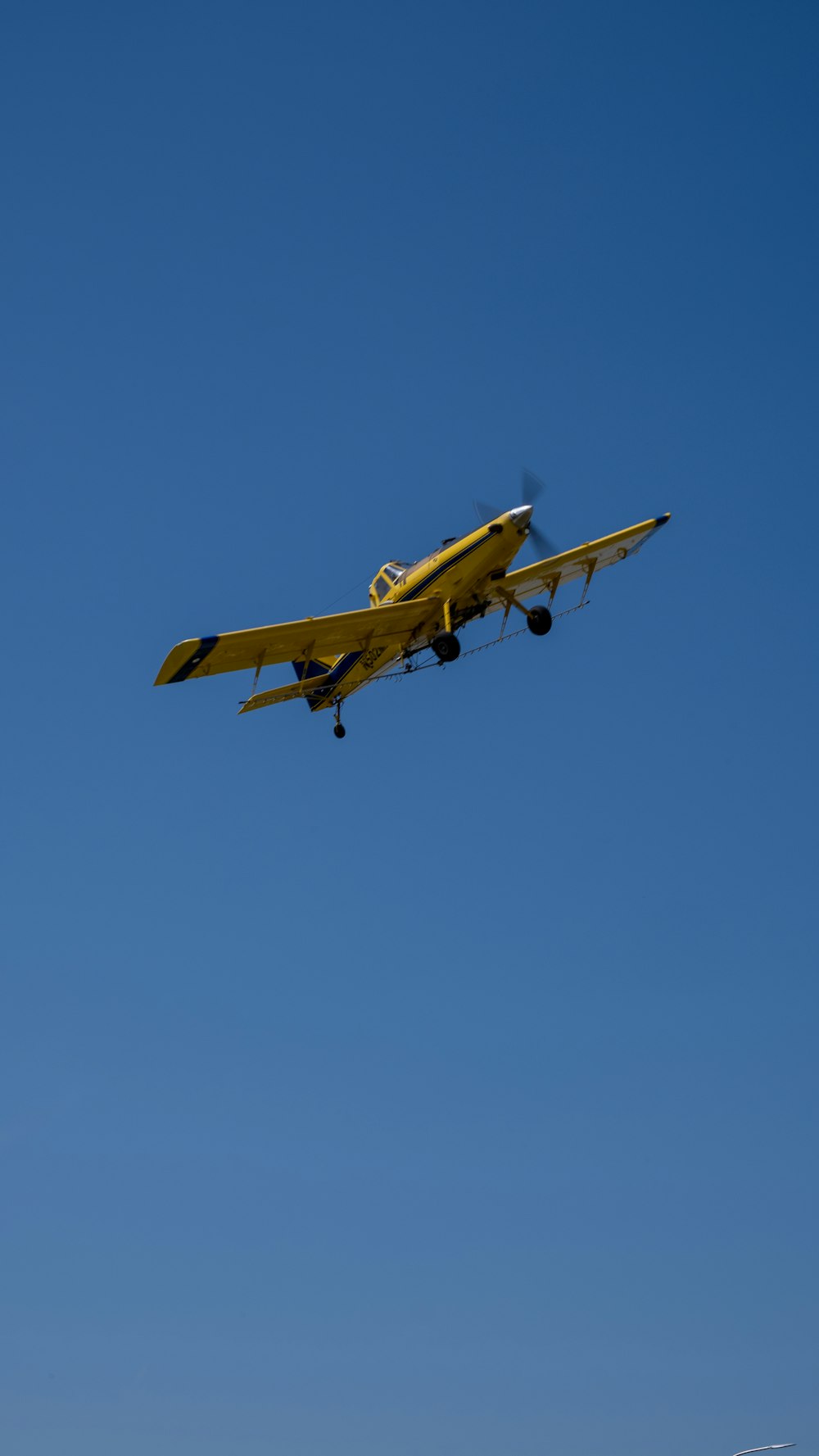 a yellow plane flying in the sky