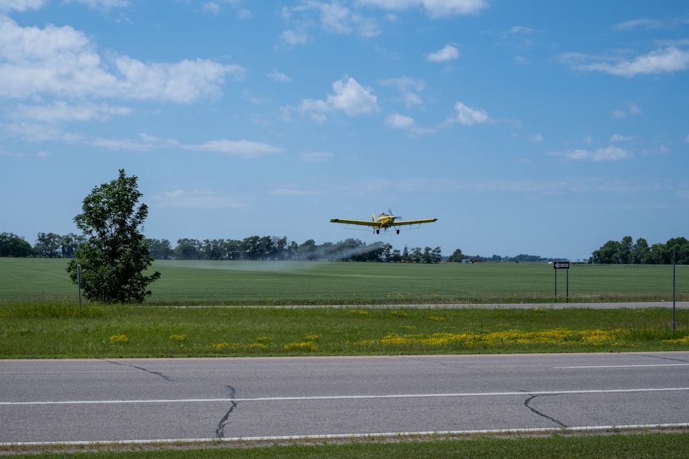 um avião amarelo voando sobre um campo