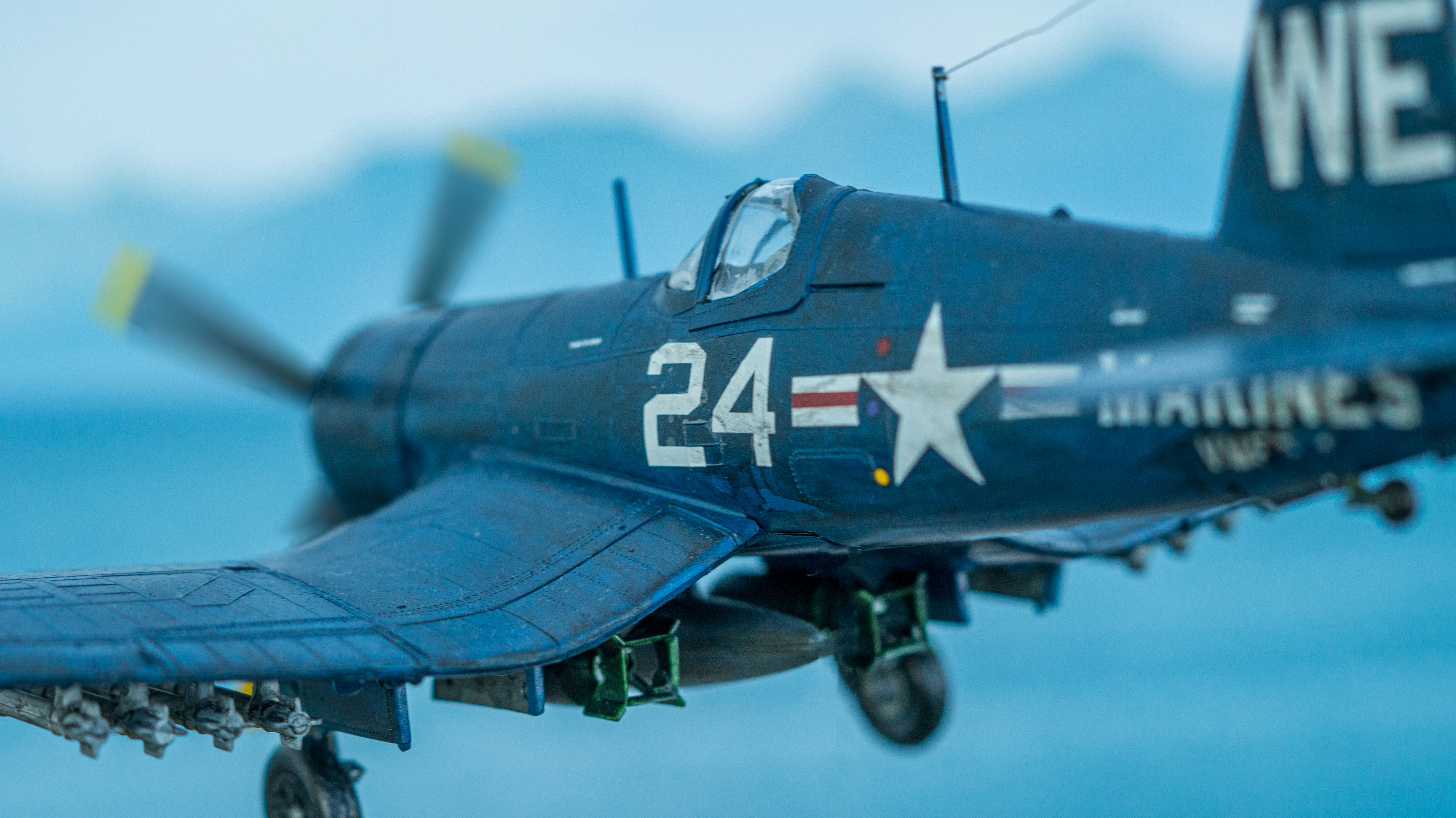 a military plane flying, Diorama of a F4U Corsair scale model flying over the sea.