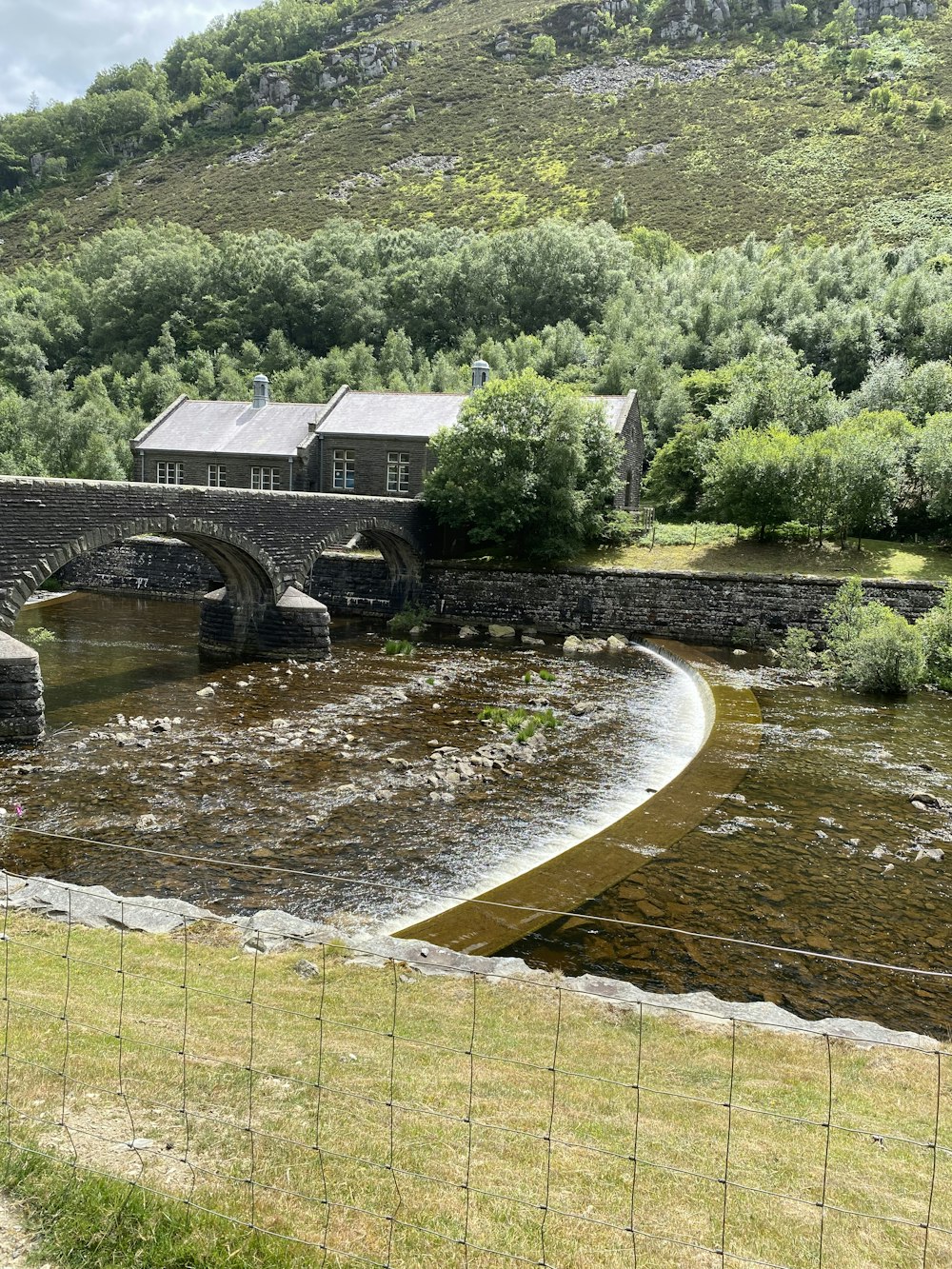 ein Fluss mit einer Brücke und einem Haus auf der anderen Seite