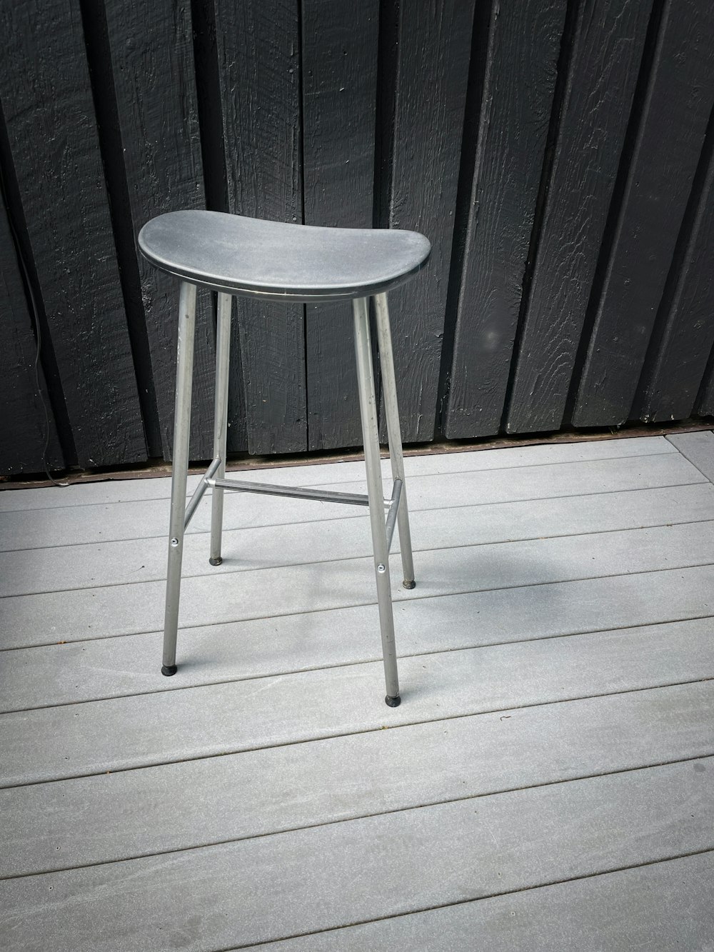 a metal stool sitting on top of a wooden floor