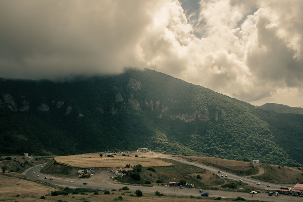 Una gran montaña verde con una carretera y coches en ella