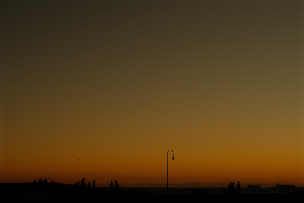 a group of people standing on a beach at sunset