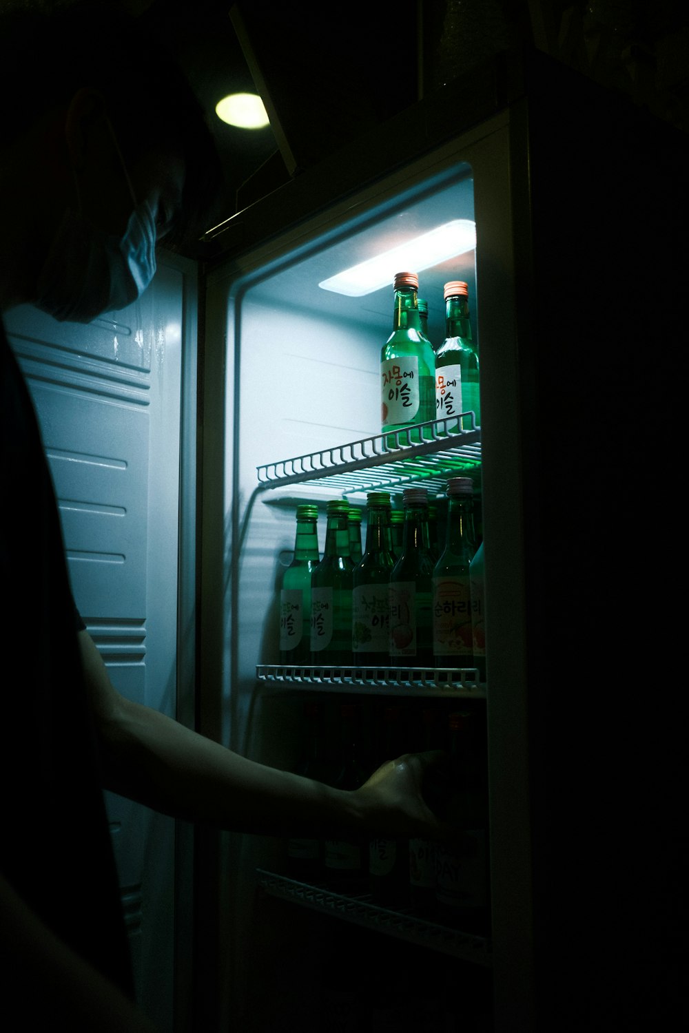 a person opening a refrigerator with bottles of alcohol