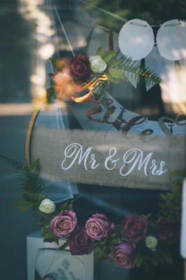 A beautifully arranged custom wedding sign made of rustic wood with delicate floral accents.