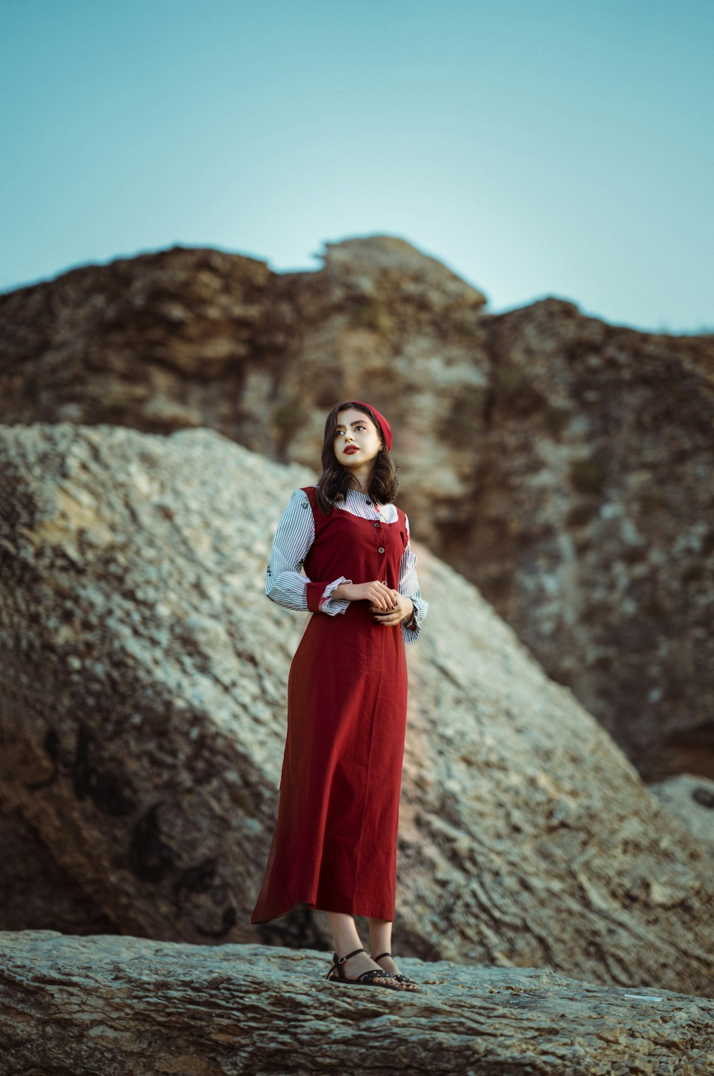 a person in a red dress standing on a rocky hillside