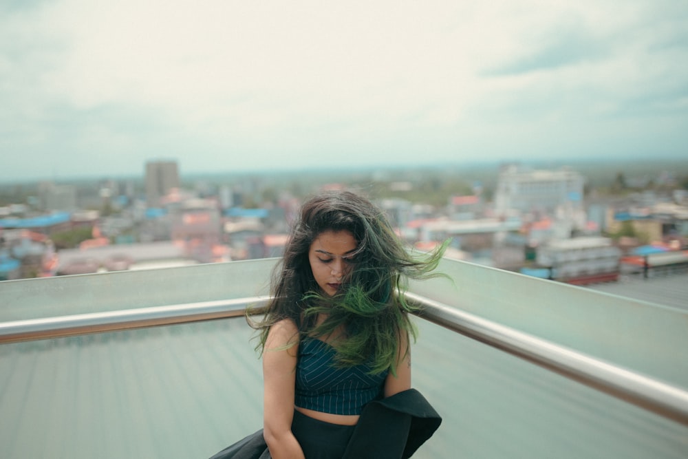 a woman leaning on a railing overlooking a city