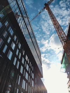 A wide-angle shot of a modern industrial building under construction with cranes silhouetted against a blue sky.