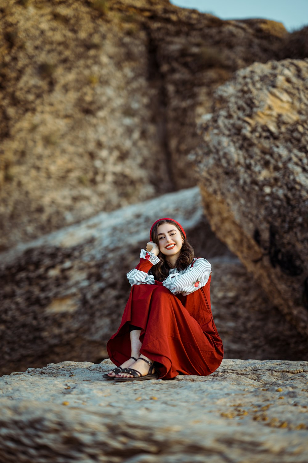 a person in a red dress sitting on a rock