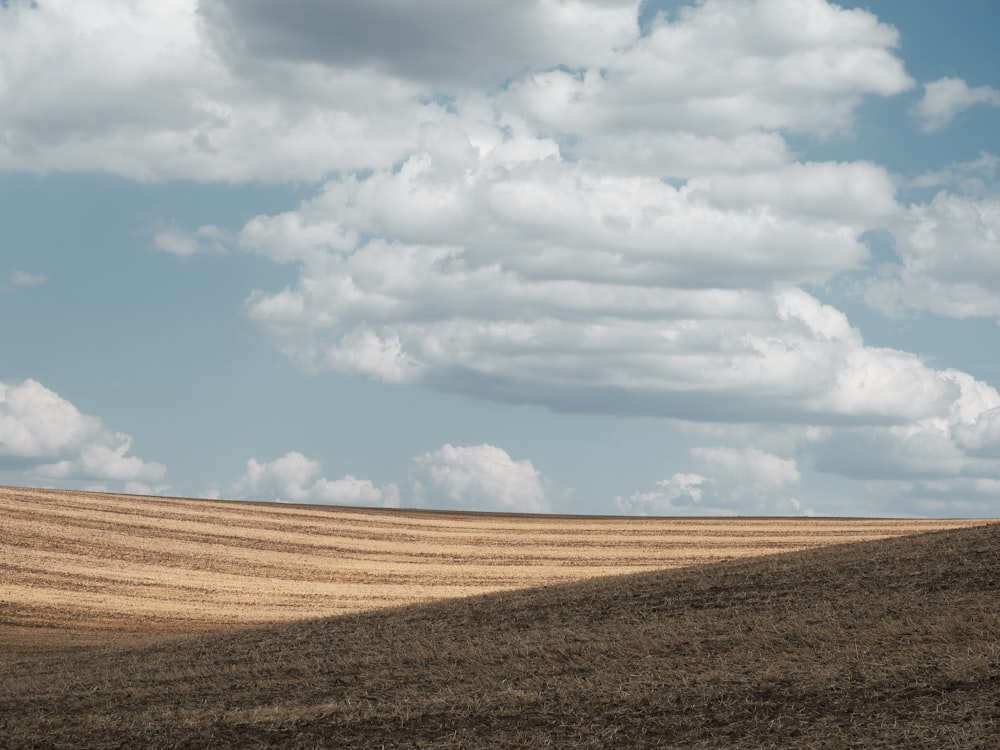 a large field with clouds in the sky