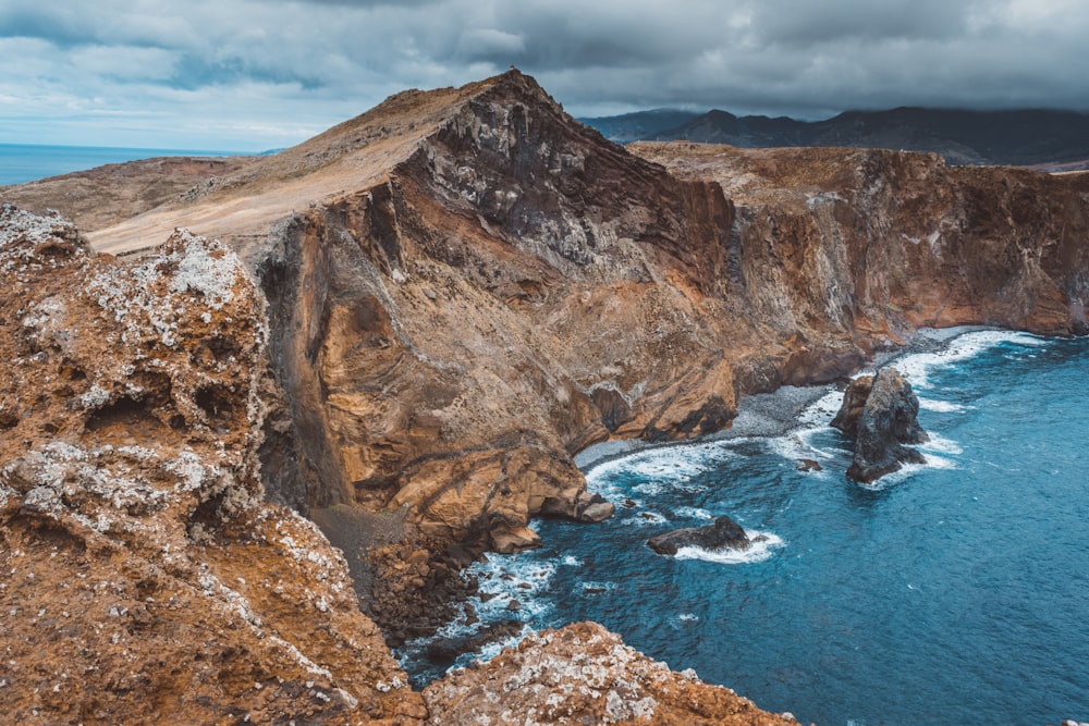 a rocky cliff next to a body of water