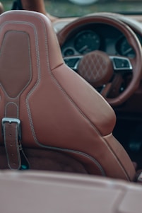 A skilled artisan carefully stitching rich leather upholstery inside a classic car interior.