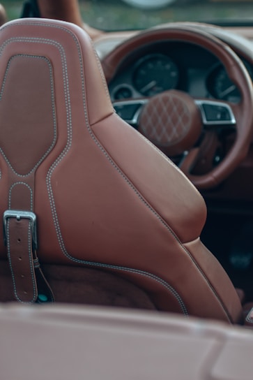 A skilled artisan carefully stitching rich leather upholstery inside a classic car interior.