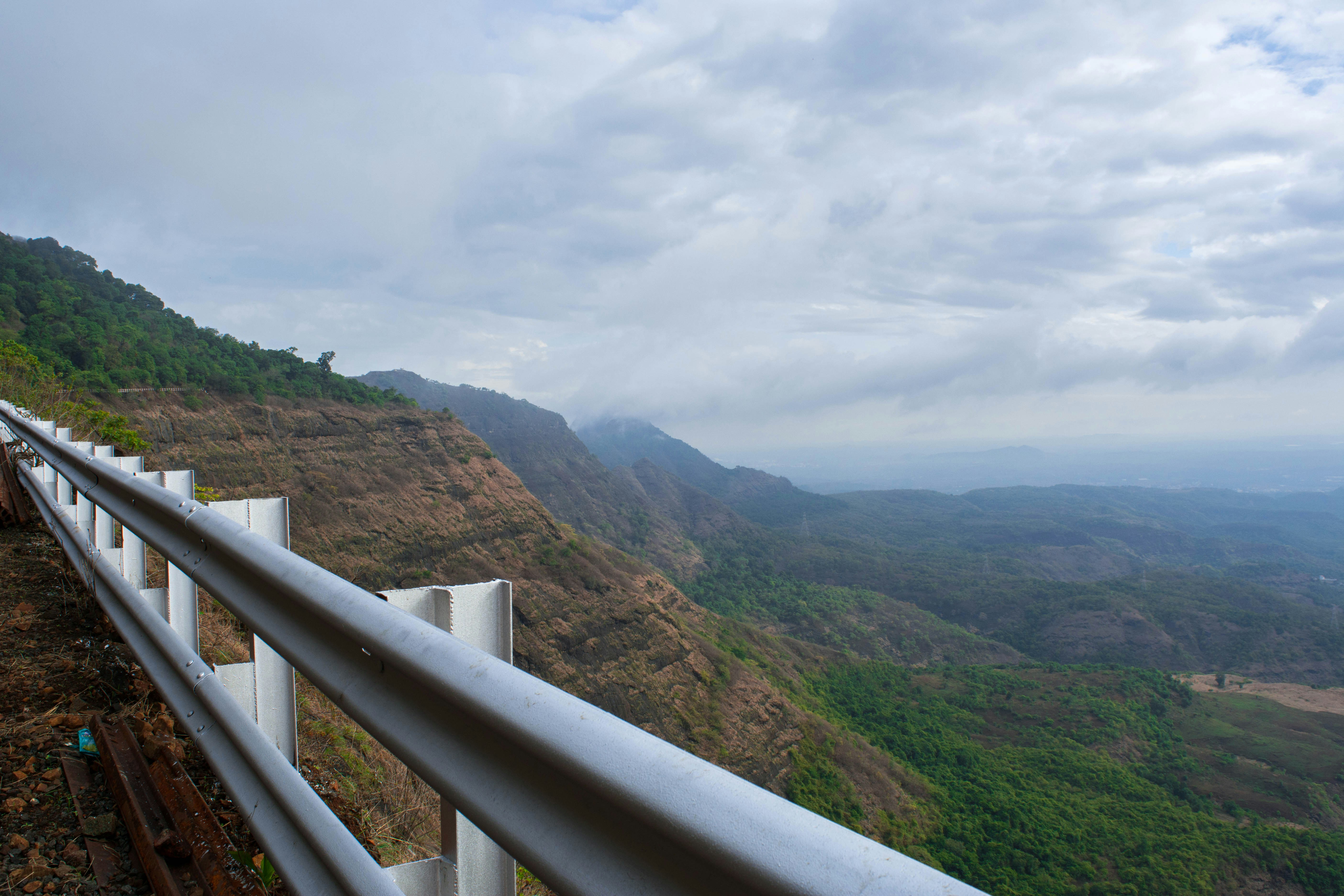 a wooden fence overlooking a valley, PEB FORT. Located 19km from Karjat, in Raigad district, of Maharashtra. This fort continues with the Malang gad, Tauli Hill and Chanderi fort of the Matheran Hill Range.  It was named after the goddess Pebi Devi and has store rooms for storing food grains and ammunition and was visited by Captain Dickinson in 1818.