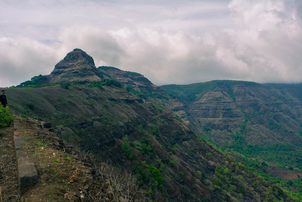 a person standing on a rock ledge overlooking a mountain range