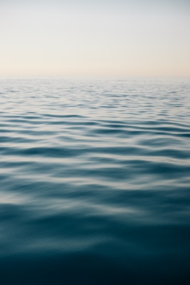 An impressionistic watercolor of a calm sea under a pale blue sky, with subtle reflections on the water.