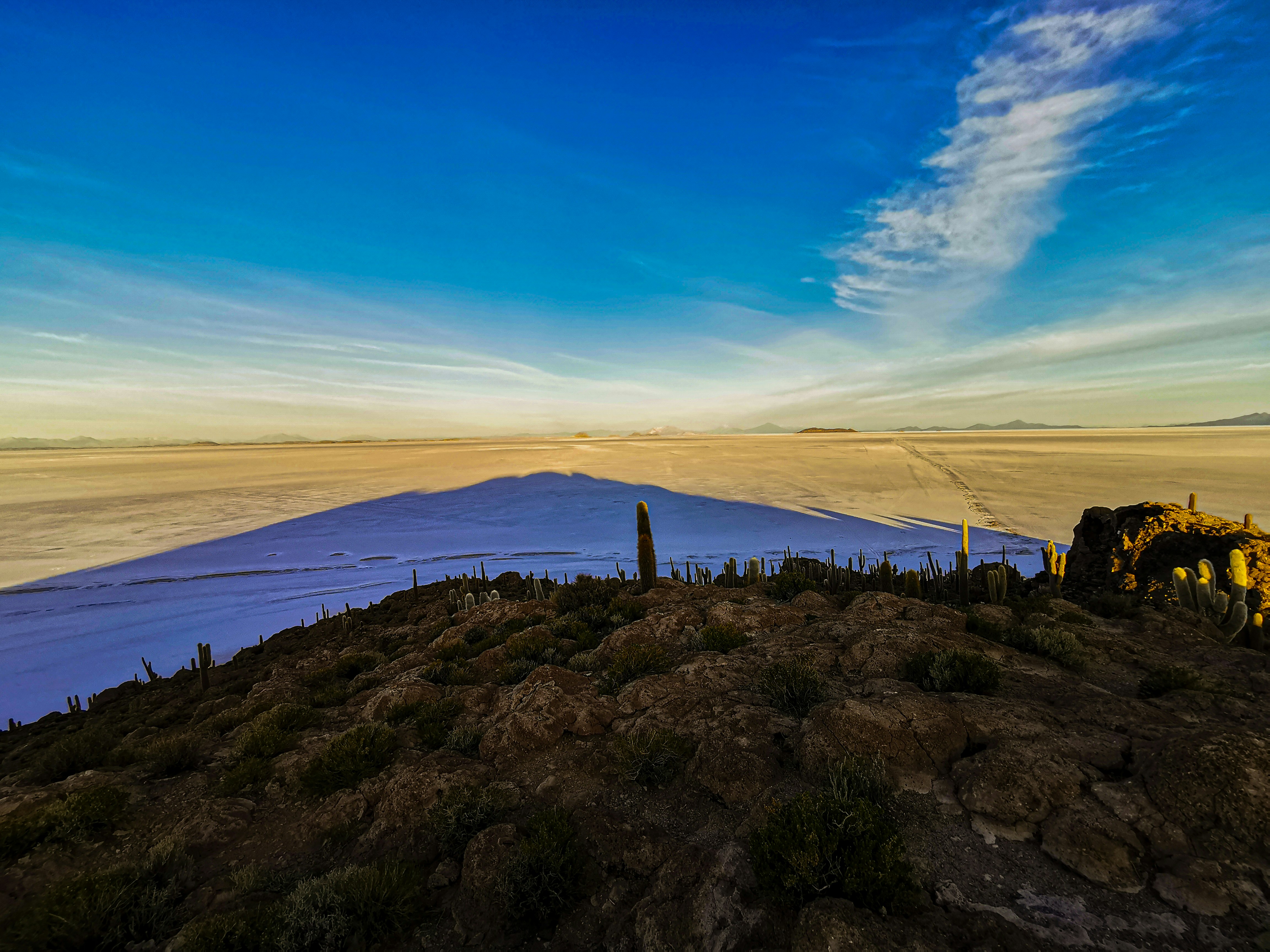 a rocky area with a body of water in the background - Uyuni