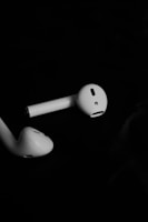 Close-up of sleek wireless Bluetooth earbuds resting on a wooden surface.