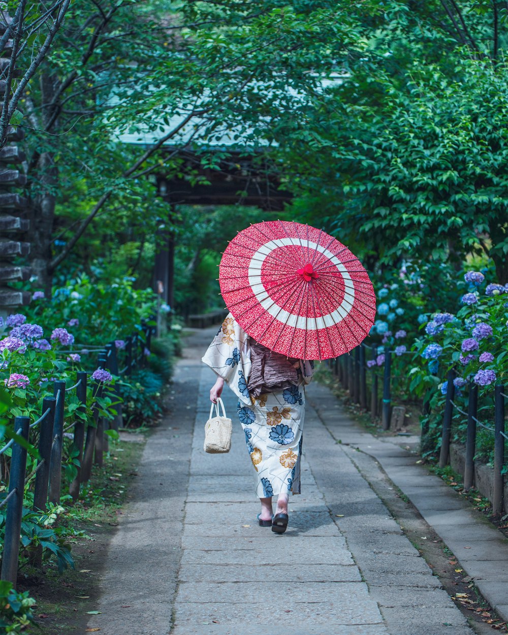 a couple of women walk down a sidewalk with an umbrella