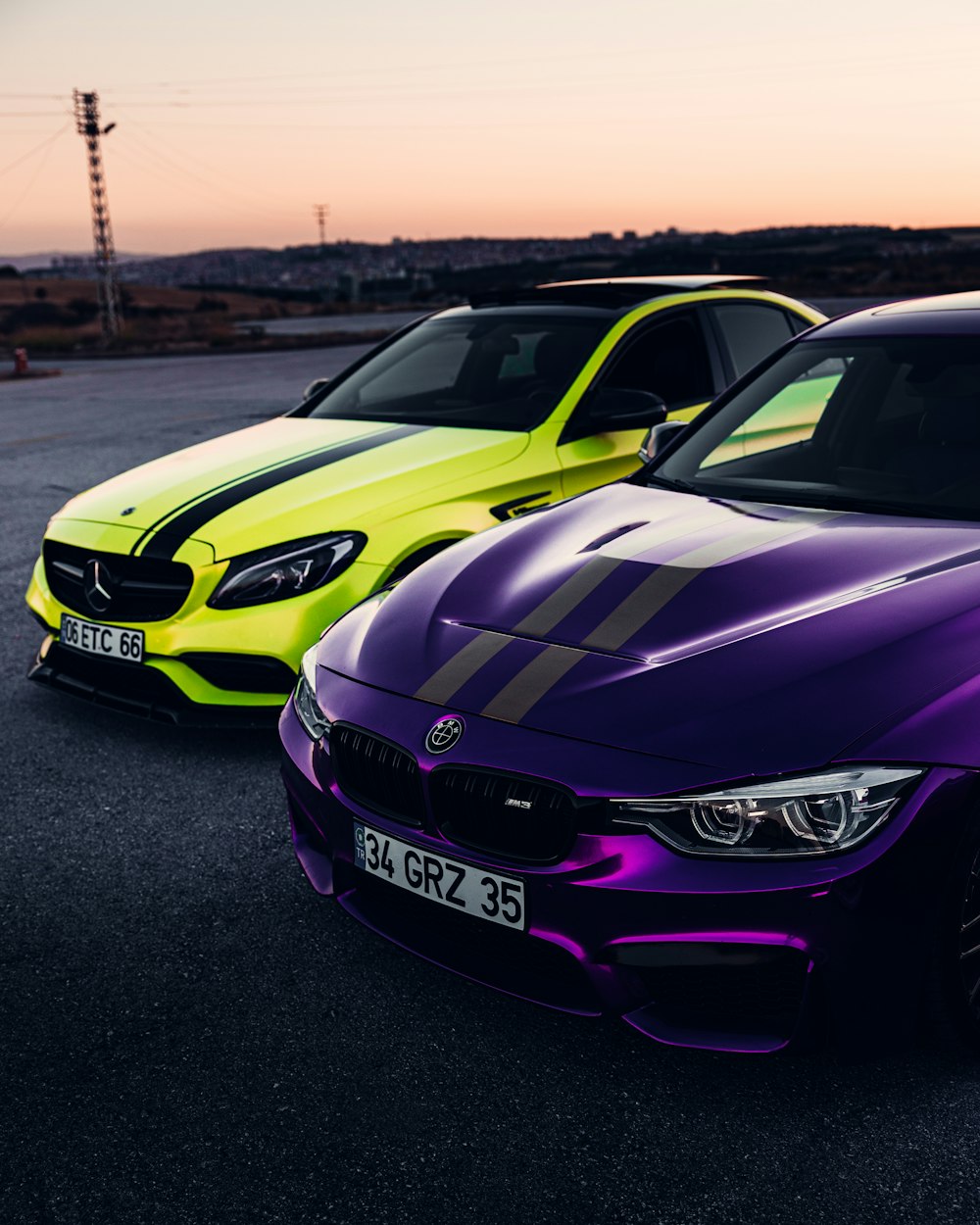 a couple of cars parked next to each other with a sunset in the background