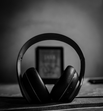 Artistic shot of headphones resting on a textured surface in monochrome.