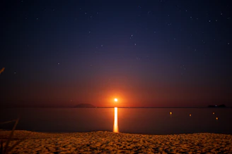 An immersive view of a private beach at Marina Smir, lit by subtle moonlight with shadows of luxury nightlife.