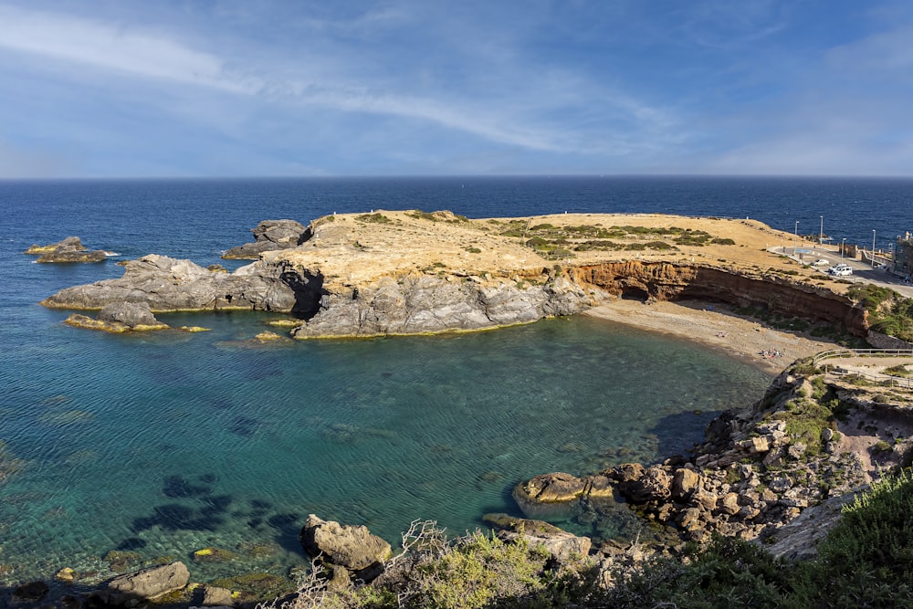 a rocky beach with a body of water in the background