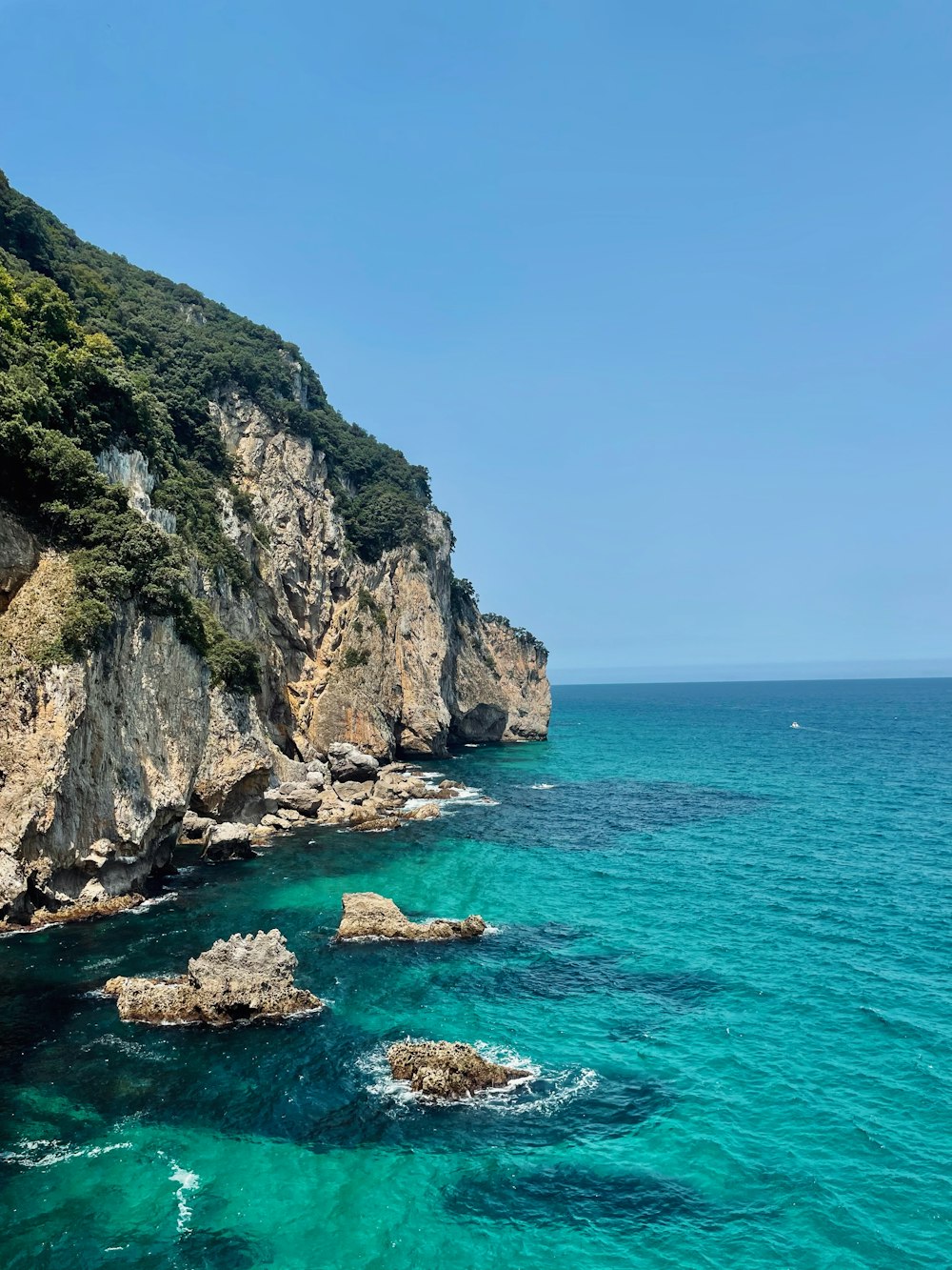 a rocky cliff next to a body of water