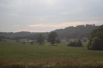 A peaceful prairie landscape with open fields and a small village in the distance.