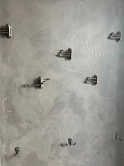 A set of modern style hooks mounted on a bathroom wall holding towels and robes.
