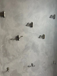 A set of modern style hooks mounted on a bathroom wall holding towels and robes.