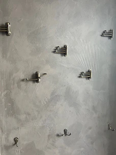 A set of modern style hooks mounted on a bathroom wall holding towels and robes.