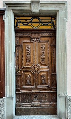 Detail of a custom wine cellar door with intricate woodwork and a vintage handle.