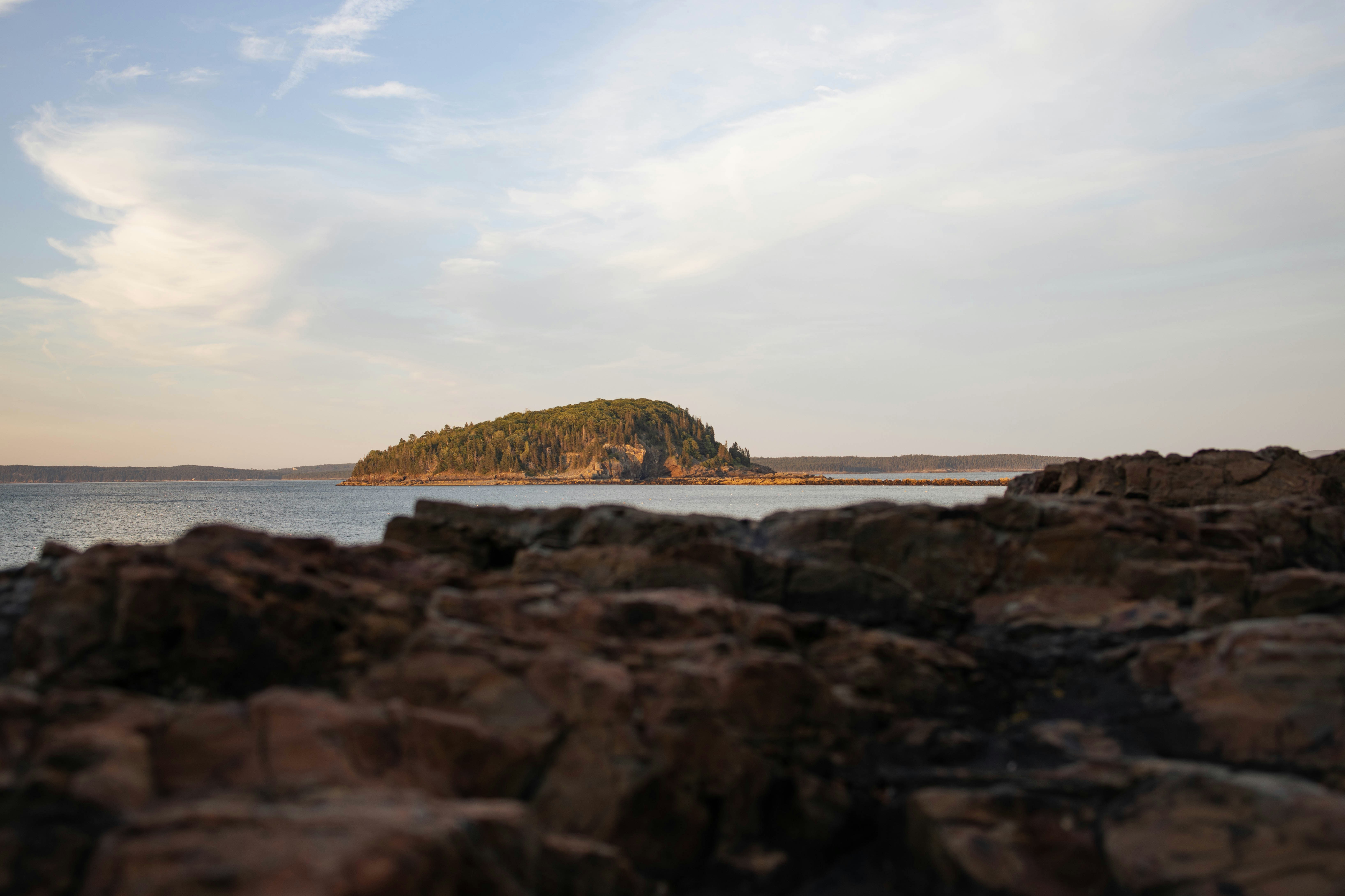 a rocky beach with a small island in the distance