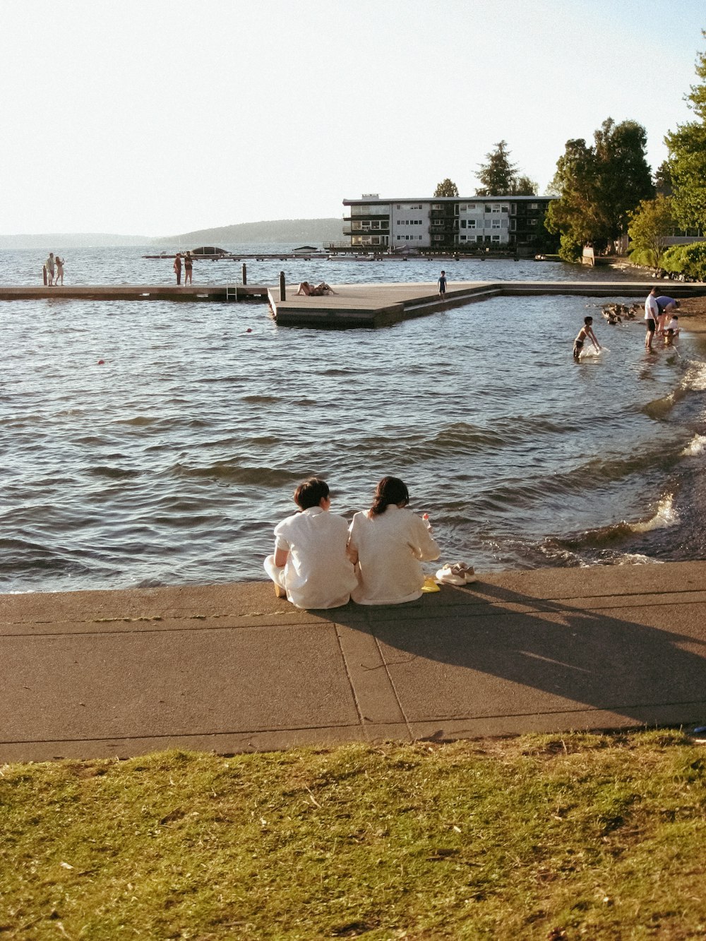 a couple sitting on a wall looking at a body of water