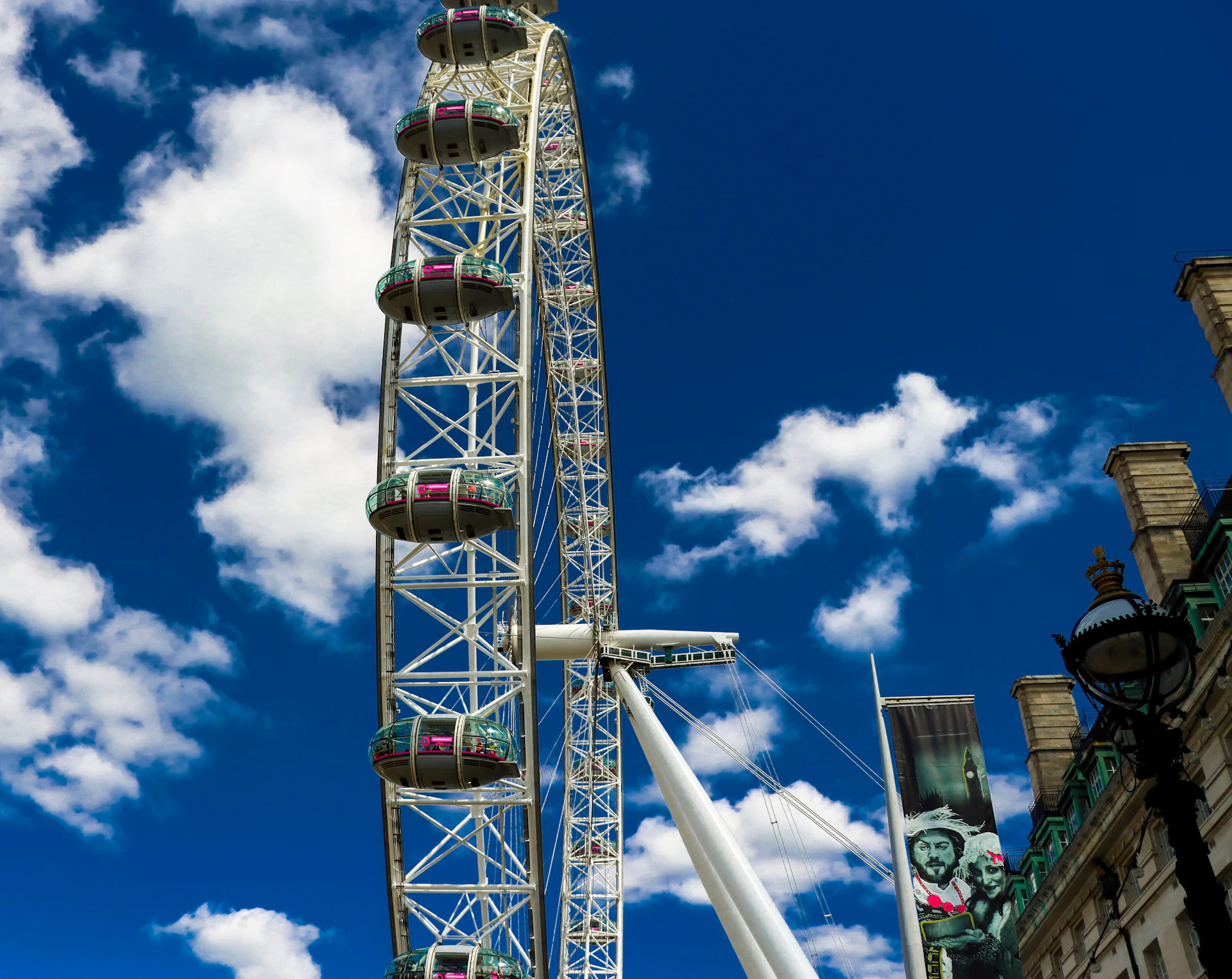 The iconic London Eye and Big Ben framed by a clear blue sky, bustling with tourists enjoying the city.