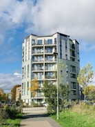 A modern residential building with large windows and landscaped gardens under a clear blue sky.