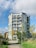 A modern multi-family building with large windows and balconies surrounded by green landscaping.