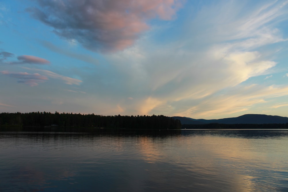 a body of water with trees and hills in the background